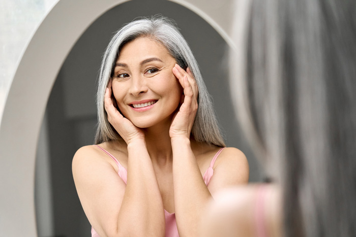 woman looking at the mirror at Sunflower Spa Injectables and Medical Aesthetics